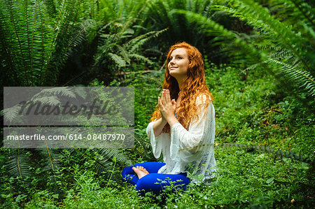 Young woman in forest practicing yoga in lotus position