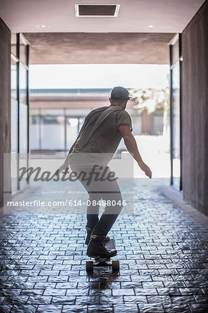 Rear view of young male skateboarder skateboarding in city