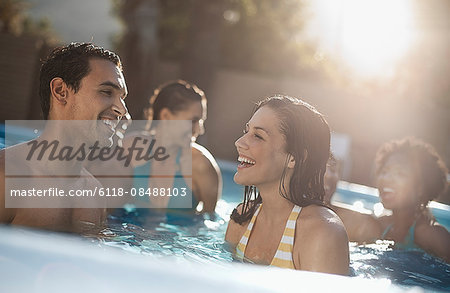 A group of young men and women in the swimming pool at the end of a hot day.