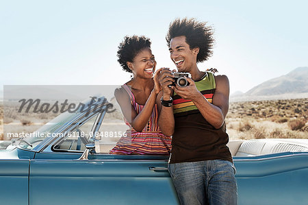 A young couple, man and woman in a pale blue convertible on the open road