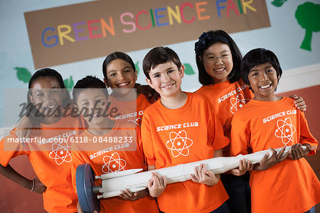 Students in the Science Club standing under the sign Green Science Fair, holding a long rocket.