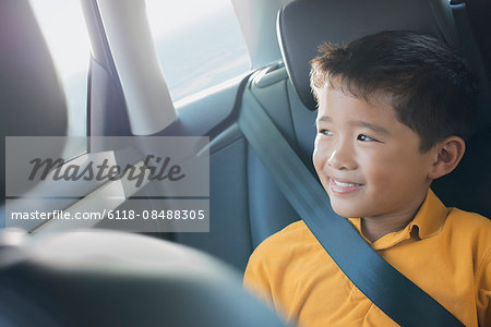 A boy sitting in a car looking out of the window.