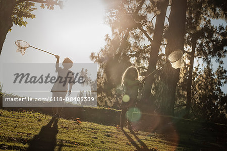 Two children using butterfly nets to try and catch butterflies.