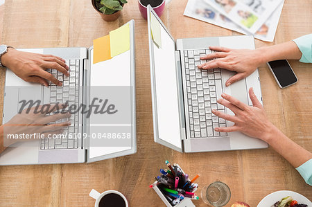 Colleagues using laptop and typing in the office