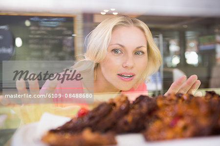 Pretty blonde choosing a cake in a cafe