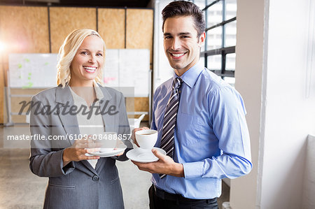 Business partners smiling over coffee at the office