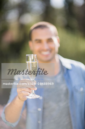 Smiling man looking at a glass of champagne in garden