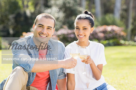 Smiling couple toasting on picnic blanket in the garden