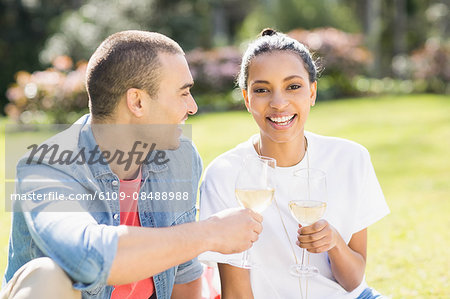 Smiling couple drinking wine on picnic blanket in the garden