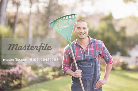 Gardener man raking the leaves in the garden