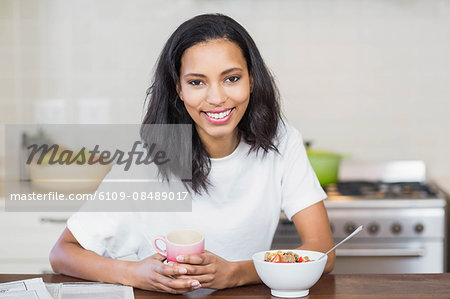 Smiling woman having breakfast in the kitchen at home