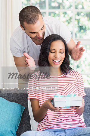 Happy couple receiving a gift on the couch at home