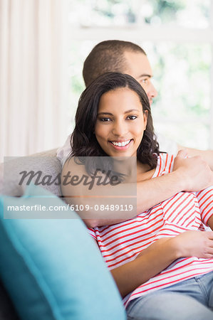 Happy couple hugging on the couch at home