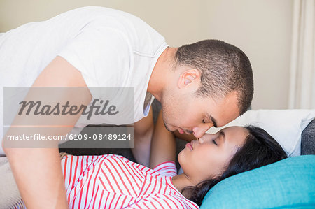 Intimate couple embracing lying on the couch at home