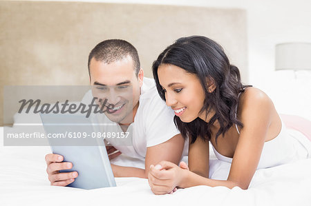 Young couple using laptop in bed at home in the bedroom