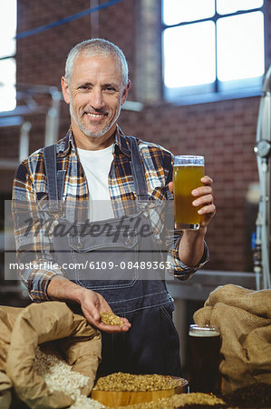 Happy brewer showing grain and produce at the local brewery
