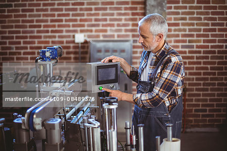 Happy brewer using machine equipment at the local brewery