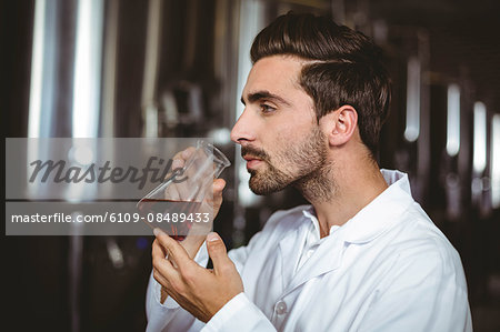 Brewer smelling beaker of beer at the local brewery