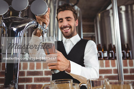 Handsome barman pouring beer in a pub