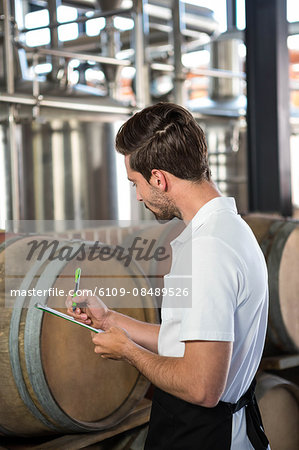 Handsome brewer checking at the barrels in a brewery Handsome brewer checking at the barrels in a brewery