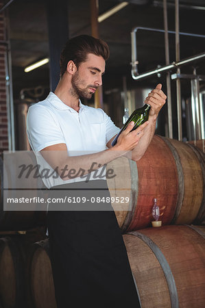 Handsome brewer checking at a wine bottle in a brewery Handsome brewer checking at a wine bottle in a brewery