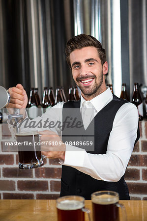 Handsome barman pouring a beer in a pub