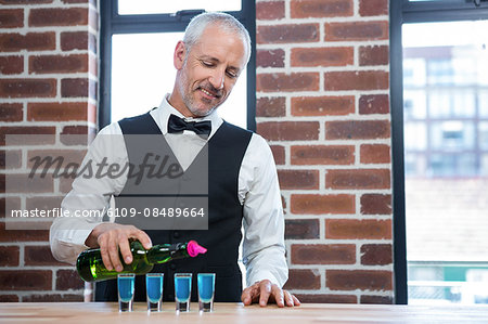 Barman pouring blue shots in a pub