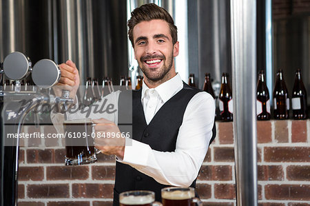 Barman pouring a pint of beer in a pub