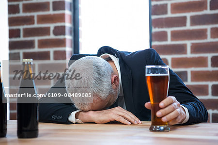 Exhausted businessman leaning on counter in a pub