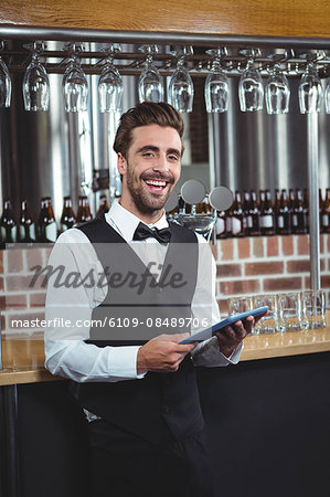 Handsome barman using tablet computer in a pub