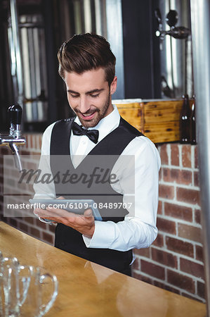 Handsome barman using tablet computer in a pub