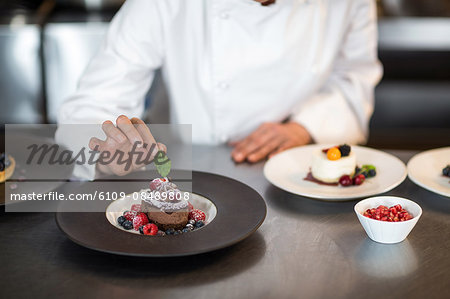 Chef putting finishing touch on dessert in a commercial kitchen