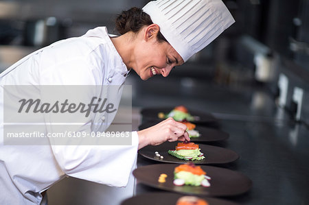 Happy chef with her dishes in a commercial kitchen