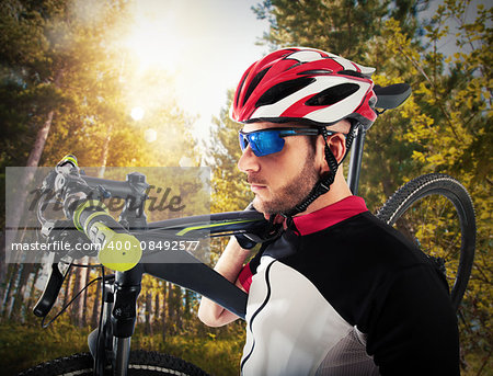 Cyclist man holds shouldered his mountain bike