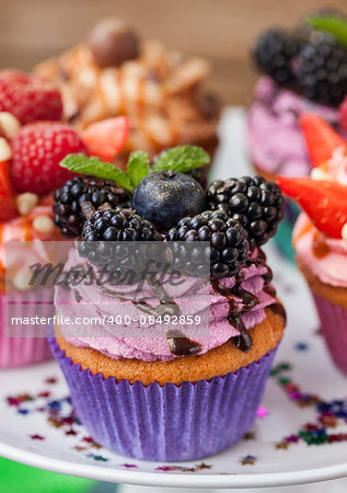 Delicious purple cupcake decorated with blueberry and blackberries