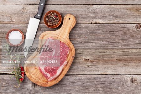 Raw beef steak and spices on wooden table. Top view vith copy space