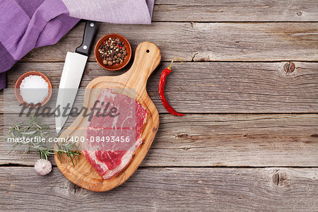 Raw beef steak and spices on wooden table. Top view with copy space