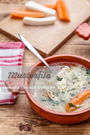 Fresh and healthy chicken soup with vegetables on wooden background