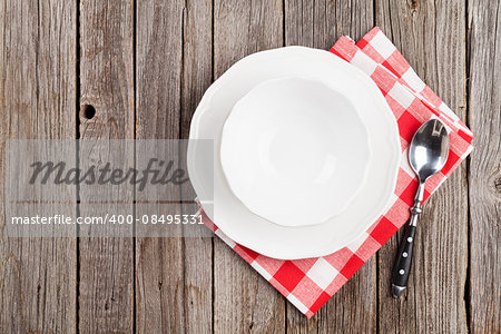 Empty plate, bowl and spoonon wooden table. Top view with copy space