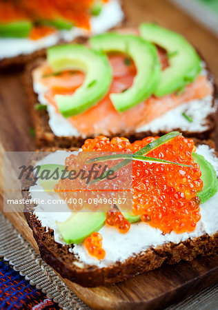 Delicious red caviar, avocado, salmon and cream cheese sandwiches