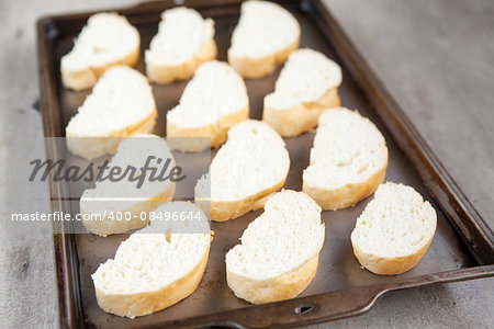 Cut french loaf bread on baking tray. Part of a series of food preparation