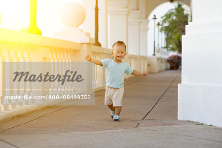 Portrait of baby boy running and smiling outdoor in sunset.