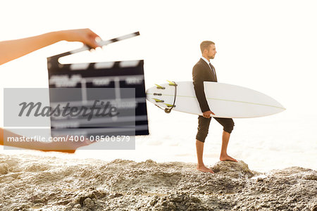 Businessman in front of a clapboard holding is surfboard. Concept about a man starting a new life.