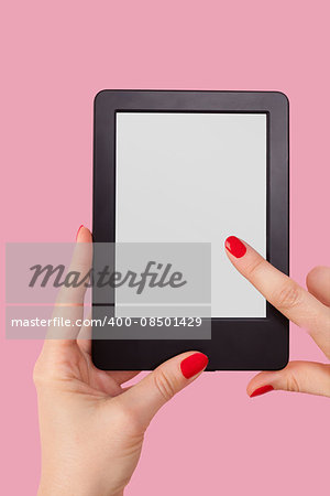 Female hand holding e reader isolated on pink background. Reading, education and learning concept.