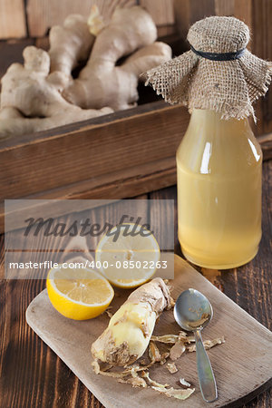 Peeled ginger root with lemons and a bottle of ginger syrup in background. Shallow dof