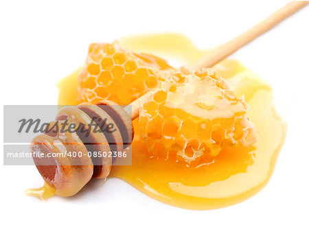Honey dipper with honeycomb close up on white