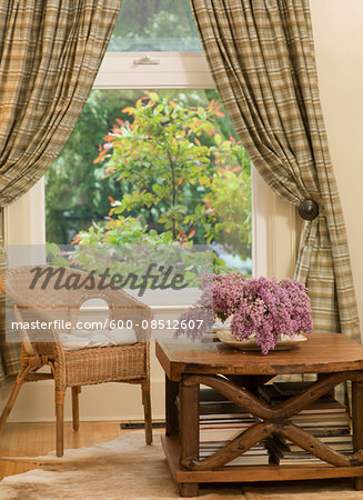 Chair and Coffee Table with Flowers by Window with Drapes in Living Room