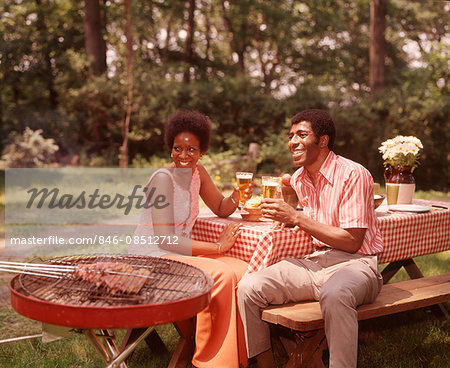 1970s SMILING AFRICAN AMERICAN COUPLE MAN WOMAN DRINKING BEER AT BACKYARD BARBECUE