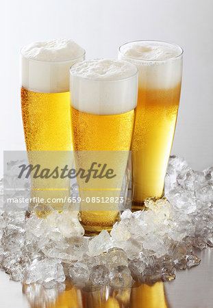 Three glasses of beer with foam on crushed ice