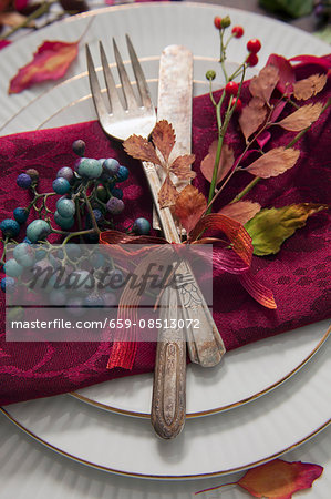 A place setting with antique cutlery decorated with autumnal leaves and berries